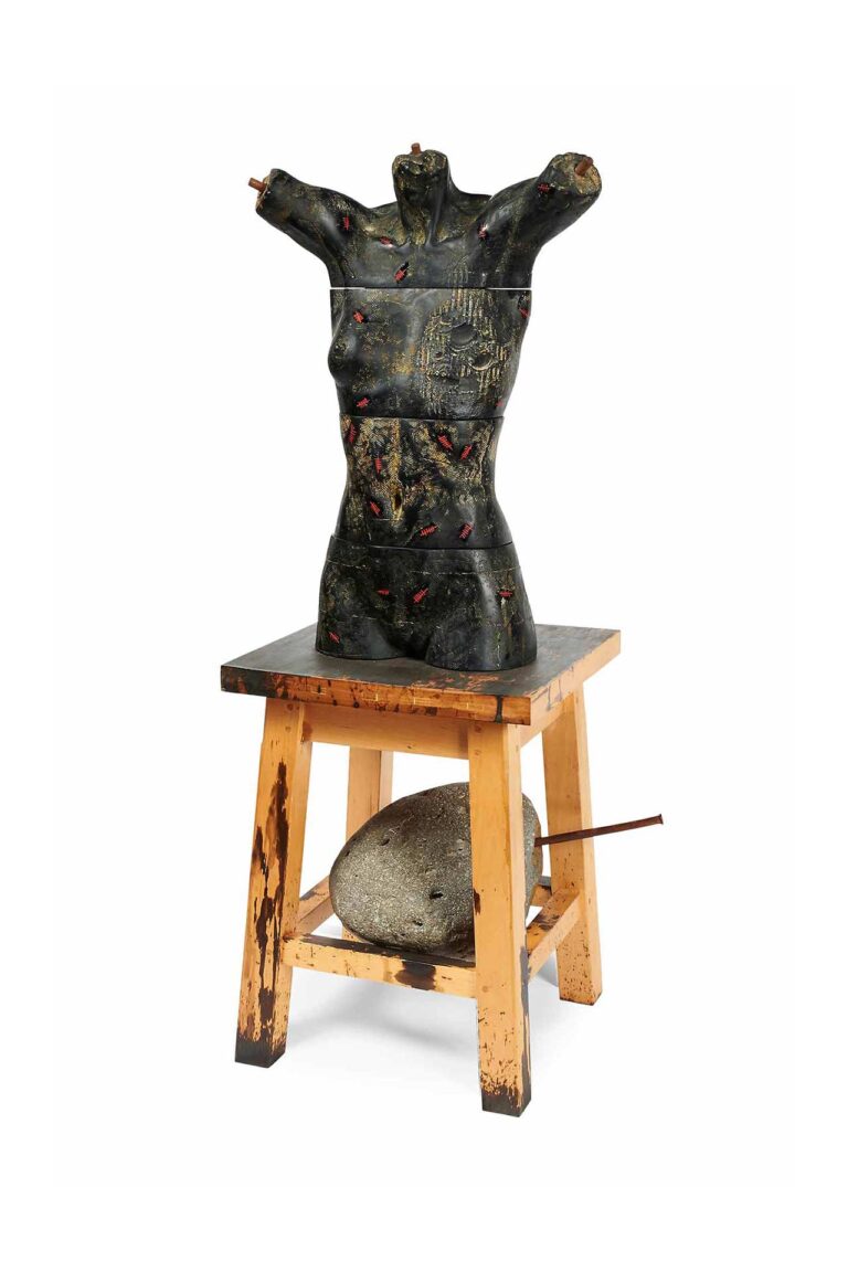A sculpture of a mannequin body on a stool with a rock.