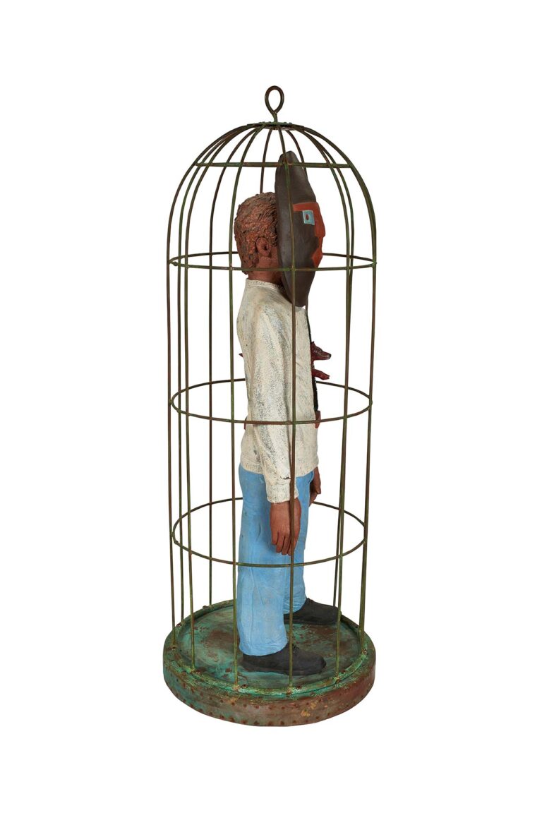 A ceramic sculpture of a figure inside a cage.