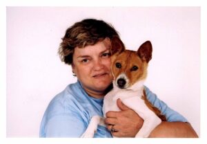 A person holding up a dog close to their face and smiling.