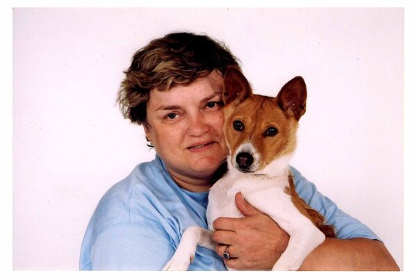 A person holding up a dog close to their face and smiling.