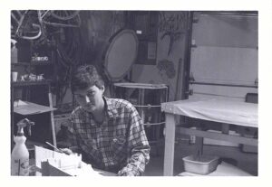 A sitting next to a sculpture they are working on.