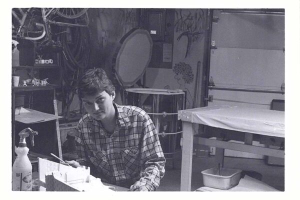 A sitting next to a sculpture they are working on.